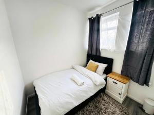 a small bedroom with a white bed and a window at The Heath Haven- Morden 4 Bedroom House Near Station High Street, Free Parking WiFi in Goodmayes