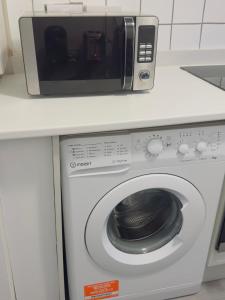 a microwave sitting on top of a washing machine at The Heath Haven- Morden 4 Bedroom House Near Station High Street, Free Parking WiFi in Goodmayes
