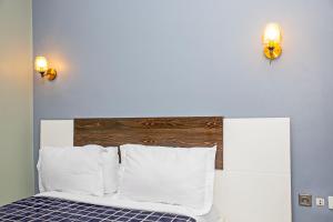 a bed with white pillows and a wooden headboard at Angel's hôtel in Douala +3 photos