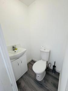 a white bathroom with a toilet and a sink at The Heath Haven- Morden 4 Bedroom House Near Station High Street, Free Parking WiFi in Goodmayes +14 photos
