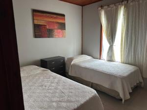 two beds in a small room with a window at Cabañas Adorable Tranquilidad in Cavalango +2 photos