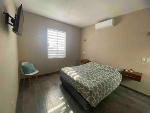 a bedroom with a bed and a chair and a window at Departamento ‘El Chulo’ en Palapa Ochoa in Loreto
