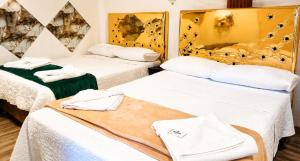 two beds in a room with white sheets and towels at Concubinas del Inca in Cajamarca +6 photos