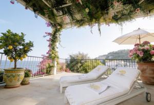 eine Terrasse mit zwei Liegestühlen und einem Sonnenschirm in der Unterkunft Prima Stella in Positano