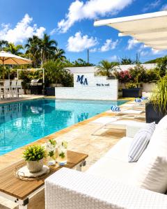 a swimming pool with white chairs and a table and a pool at Malika Apartments in Westpunt