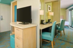 a room with a desk with a television and chairs at Waikiki Circle Hotel by Castle in Honolulu