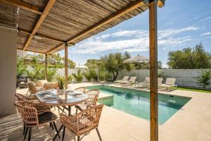 a patio with a table and chairs next to a swimming pool at Villa Romas 2 by Villa Plus in Vasilikos