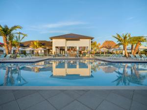 a swimming pool with palm trees and a pavilion at Villatel Orlando Resort in Orlando