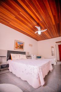 a bedroom with a large bed with a wooden ceiling at Pousada Uai vem ser feliz in Alagoa