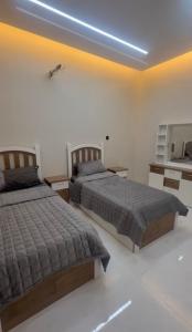 a bedroom with two beds and a mirror at شقق ورد in Al Barkah