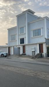a large white building with a car parked in front of it at شقق ورد in Al Barkah