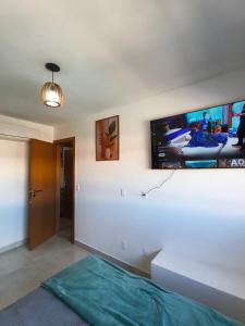a bedroom with a flat screen tv on the wall at Duplex Praia de Imbassaí in Mata de Sao Joao