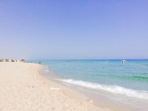 a sandy beach with the ocean and boats in the water at Dar Meriem in Korba