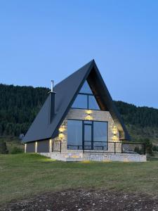 a house with a black roof on a grass field at V Chalet in Žabljak