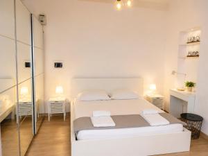 a white bedroom with a bed and two tables at Le case di Rebecca in Palermo