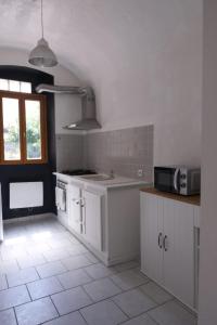 a kitchen with white cabinets and a sink and a microwave at Les Vans Centre-village in Les Vans