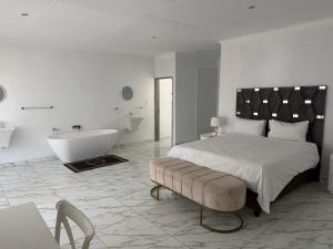 a white bedroom with a bed and a bath tub at Veesboutiquehotel in eMalahleni