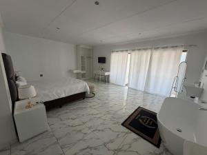 a white bedroom with a bed and a bathroom at Veesboutiquehotel in eMalahleni