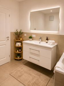a white bathroom with a sink and a mirror at Ena Appartements in Altenmarkt im Pongau +12 photos