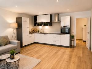 a kitchen with white cabinets and a living room at Ena Appartements in Altenmarkt im Pongau
