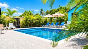 a swimming pool with chairs and umbrellas next to a house at Spacious Home with Private Pool in San Felipe de Puerto Plata
