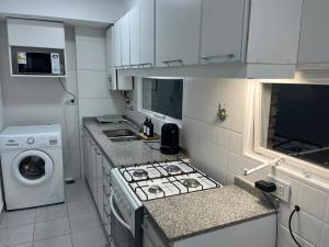 a kitchen with a stove and a washing machine at Torre Parque Apartamento in Morón