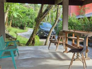 a porch with chairs and a table and a car at Charme e conforto - surf pertinho de casa in Garopaba