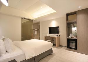 a bedroom with a bed and a desk and a television at Dandy Hotel-Daan Park Branch in Taipei