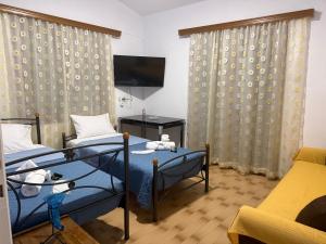 a room with two beds and a tv and a couch at Markella STONE & LIGHT Skoutari-Mani in Skoutari