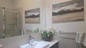 a bathroom with a sink and a mirror and flowers at Sunset in Pakenham in Pakenham +10 photos
