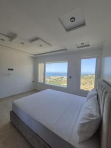 a white bedroom with a large bed and two windows at Villa mnar 3 chambre en haut in Tangier