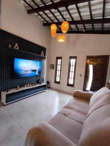 a living room with a large flat screen tv at Chácara Sol e Lua dos três Morros in Piatã