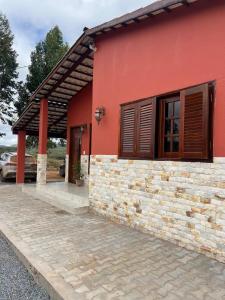 a red house with a stone wall at Chácara Sol e Lua dos três Morros in Piatã