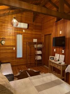 a bedroom with wood paneling and a television and a bed at Sítio Brisa da Serra Conforto e Tranquilidade in Lauro Müller