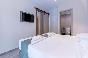 a white bedroom with a large bed and a television at Afytos Rooms in Afitos