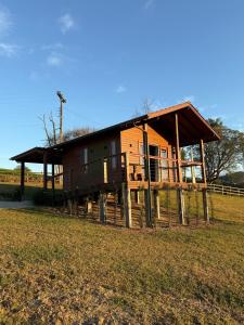 a wooden house on logs in a field at Sítio Brisa da Serra Conforto e Tranquilidade in Lauro Müller