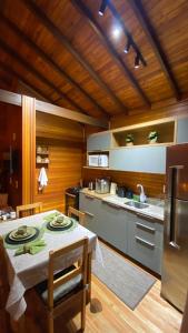 a kitchen with a table and a kitchen with a refrigerator at Sítio Brisa da Serra Conforto e Tranquilidade in Lauro Müller