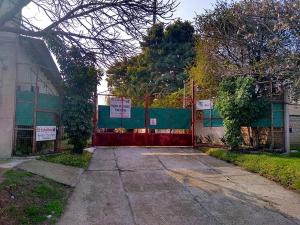 a fence with a red gate in front of a building at La Ricarda in Gualeguaychú