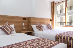 a hotel room with two beds and a window at Apachetas Hotel in Machu Picchu