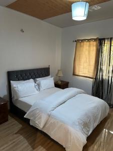 a bedroom with a large white bed and a window at Rashlie apartment in Freetown