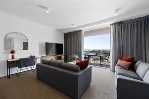 a living room with a couch and a desk and a television at Quest Mackay on Gordon in Mackay