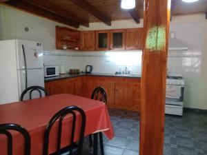 a kitchen with a red table and a white refrigerator at La cabaña de ines in El Bolsón