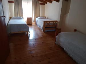 a room with two beds and a wooden floor at La cabaña de ines in El Bolsón