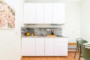 a kitchen with white cabinets and a table and chairs at Flores 21 Apartments Príncipe Real in Bicas