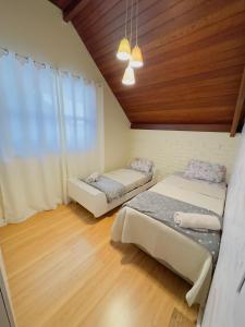 two beds in a room with wooden floors at Deruci Chale in Nova Friburgo