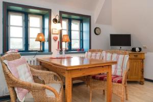 a dining room with a wooden table and wicker chairs at Hansen-Hof-Wohnung-2 in Tinnum