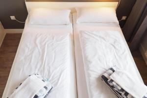 two beds in a room with white sheets and towels at Appartement-155 in Westerland