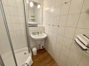 a white bathroom with a sink and a shower at Appartement-155 in Westerland +1 photo