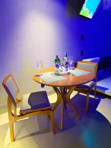 a wooden table with two chairs and wine glasses at Khalifa Experience Motel in Itumbiara