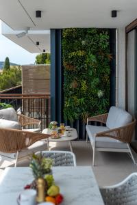 a patio with tables and chairs and a green wall at Royal Oak beachfront residence Trogir Seget Vranjica in Seget Vranjica